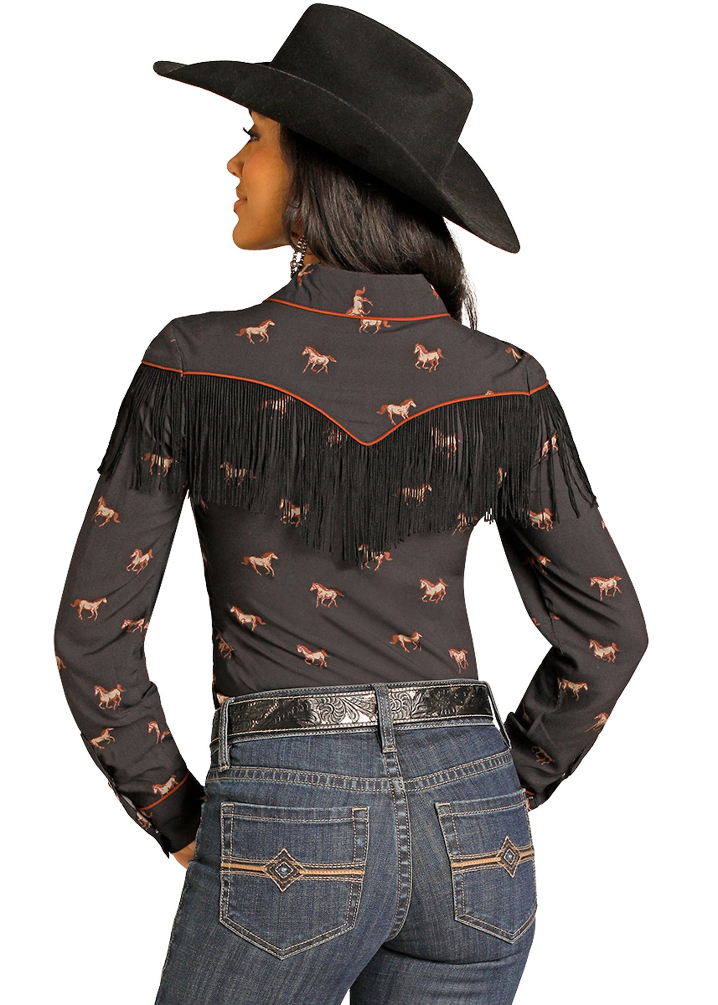 Woman wearing a black fringed blouse with horse patterns and blue jeans on a white background