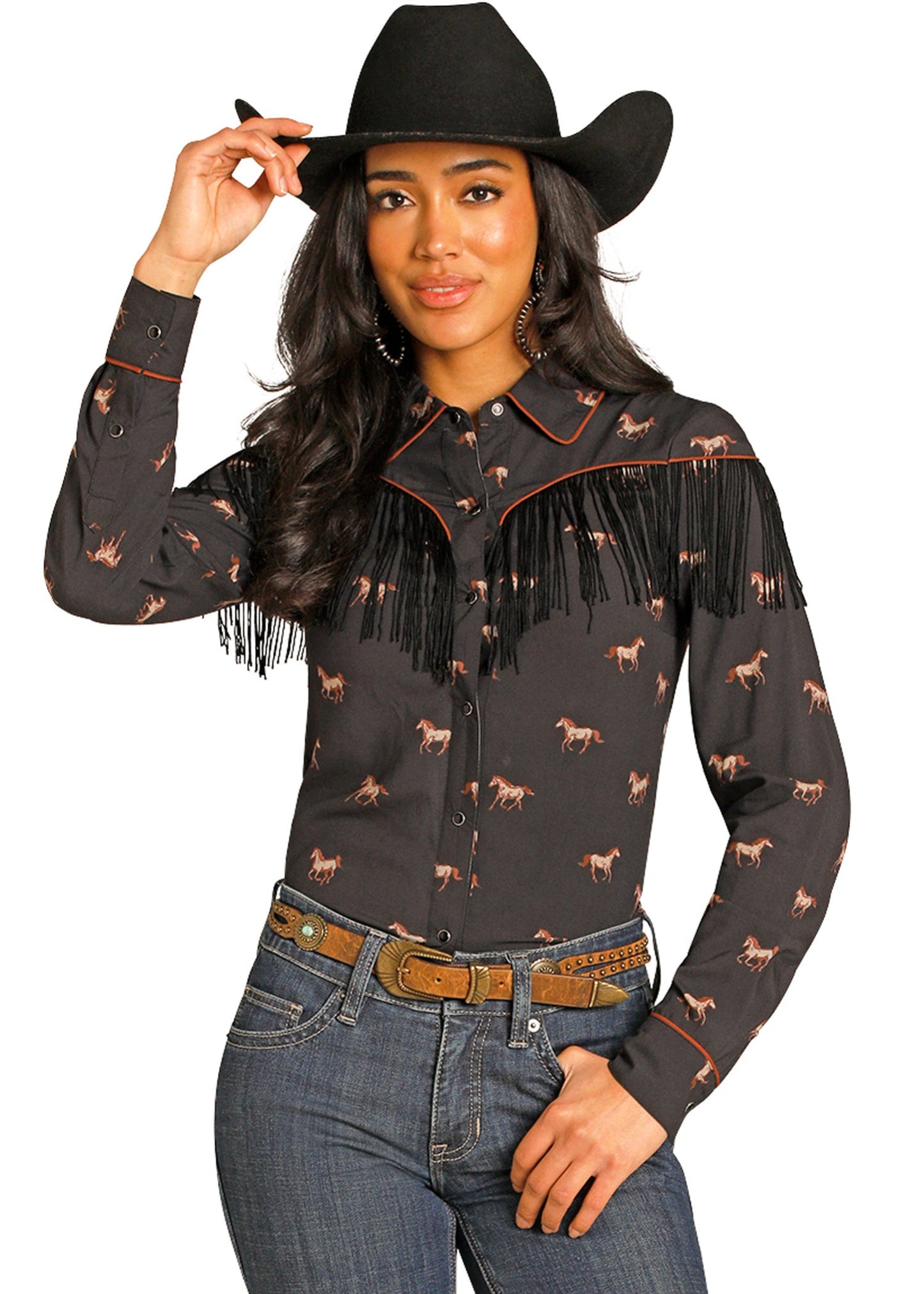 Woman wearing a black fringed shirt with horse patterns and a black cowboy hat on a white background