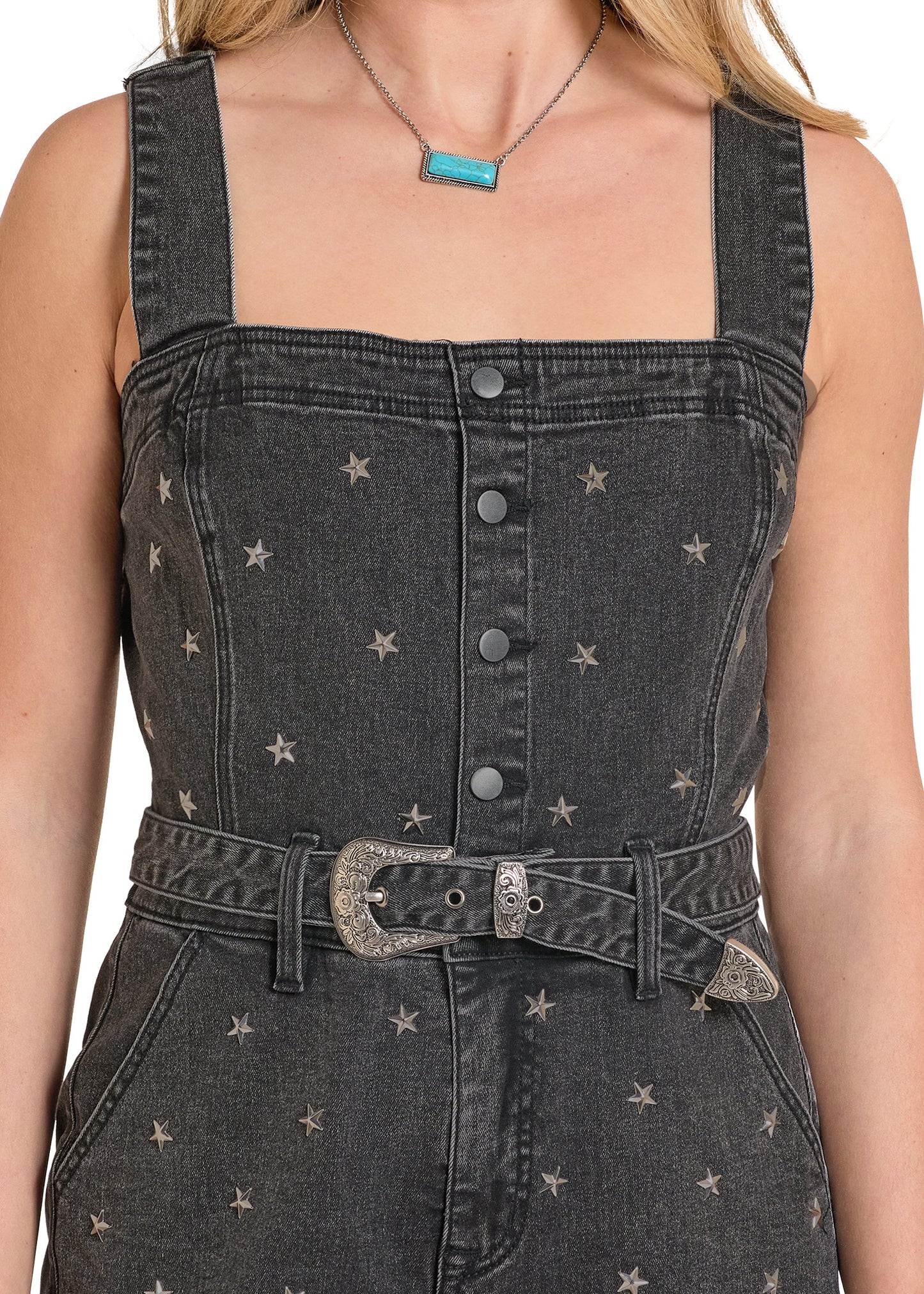 Black denim overalls with star patterns worn by a person on a white background