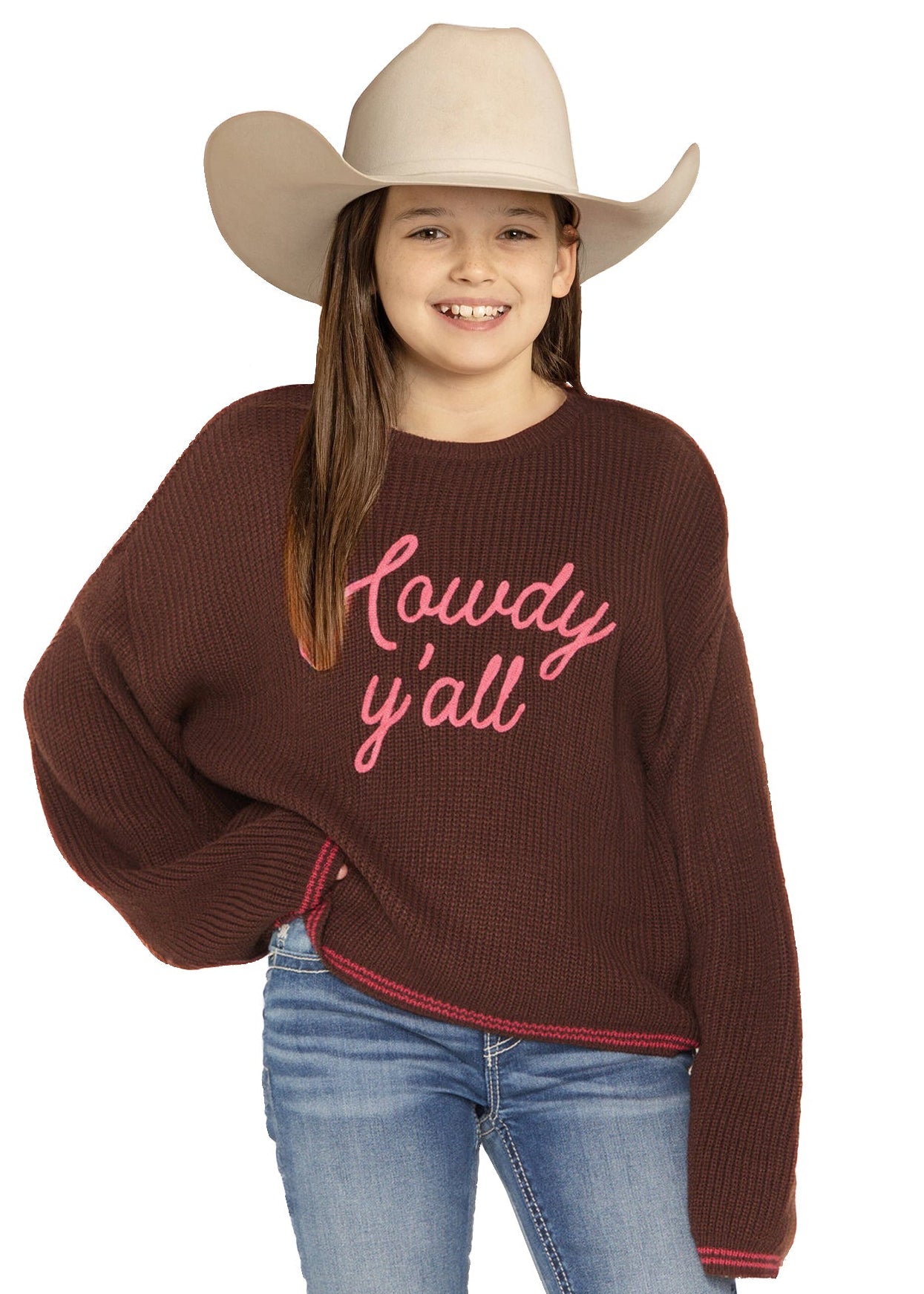 Girl wearing a brown sweater with 'Lowdy y'all' text, blue jeans, and a beige cowboy hat on a white background