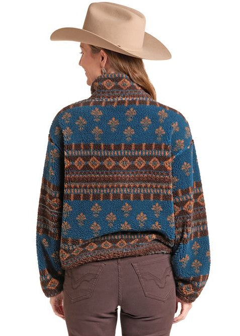 A woman shown from the back wearing a patterned long-sleeve sweater, brown flared pants, and a beige cowboy hat against a plain white background.