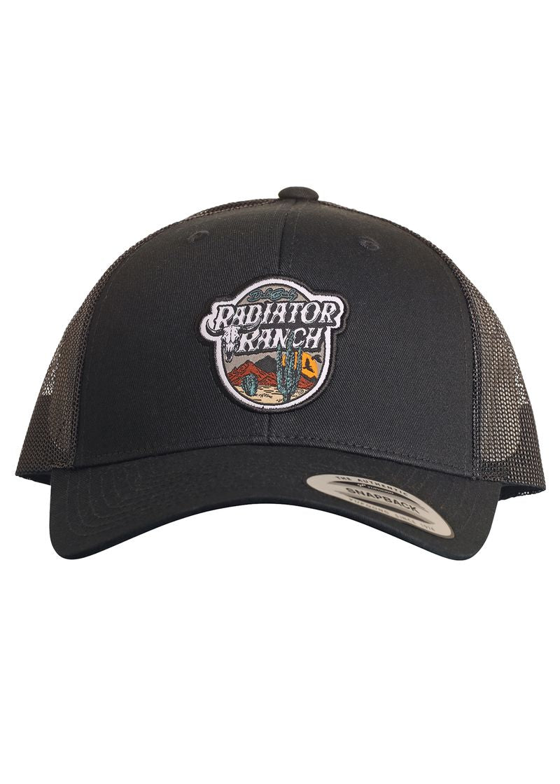 The Dale Brisby Black Radiator Ranch Cap by Rock & Roll Denim features black mesh, a snapback closure, and a front patch with a western scene—mountains, cacti, and a building. Perfect for fans of Dale Brisby.