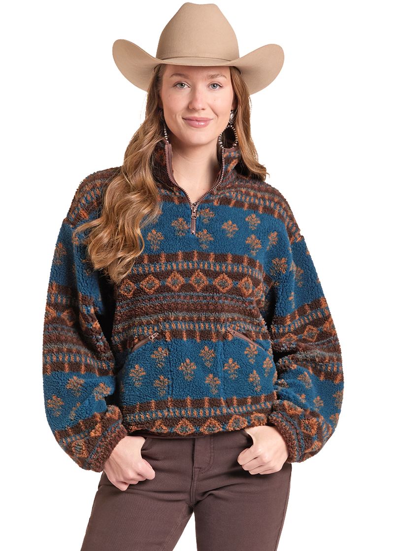 A woman wearing a blue and brown patterned quarter-zip fleece pullover sweater, brown pants, and a tan cowboy hat, photographed against a plain white background.