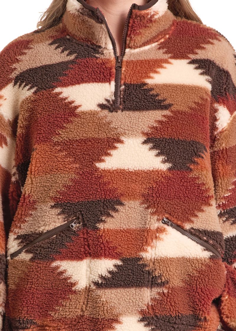 Close-up of a sherpa fleece quarter-zip pullover with a Southwestern geometric pattern in rust orange, brown, cream, and dark brown.