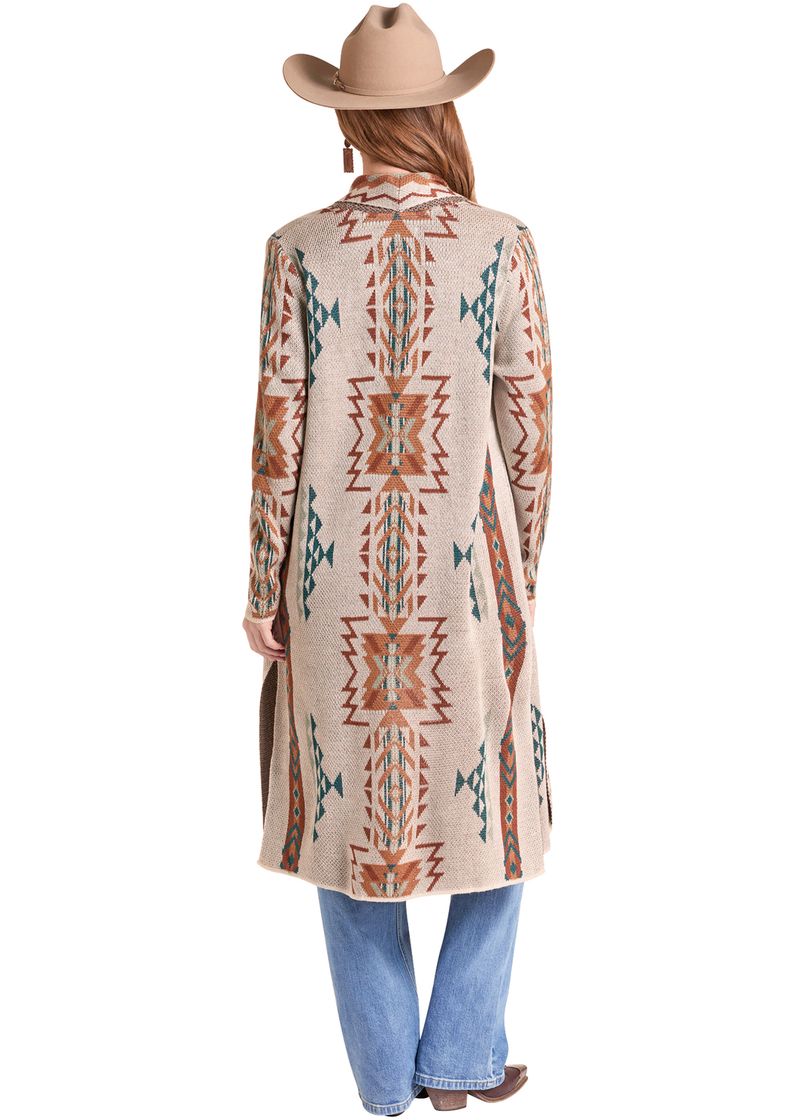 A woman shown from the back wearing a long beige cardigan with a Southwestern geometric pattern in rust orange, teal, and cream.