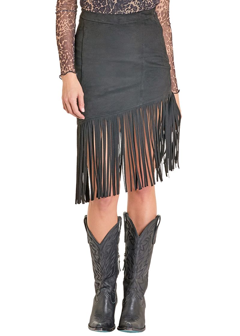 Someone stands against a white background wearing the Rock & Roll Denim Asymmetrical Microsuede Fringe Skirt in black, paired with a sheer animal print long-sleeve top and black cowboy boots. The skirt has long fringe along the hem.