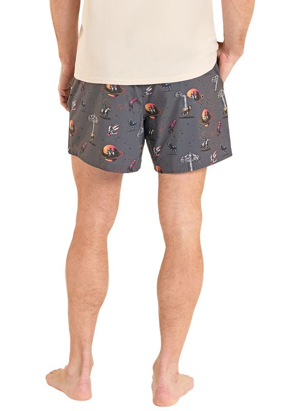 Man wearing a beige t-shirt and patterned shorts on a white background